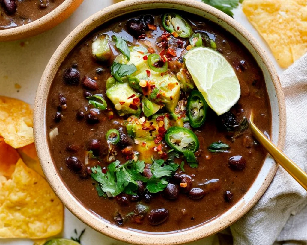 Home 8 Black bean soup topped with avocado, jalapeño, cilantro, lime, and red pepper flakes
