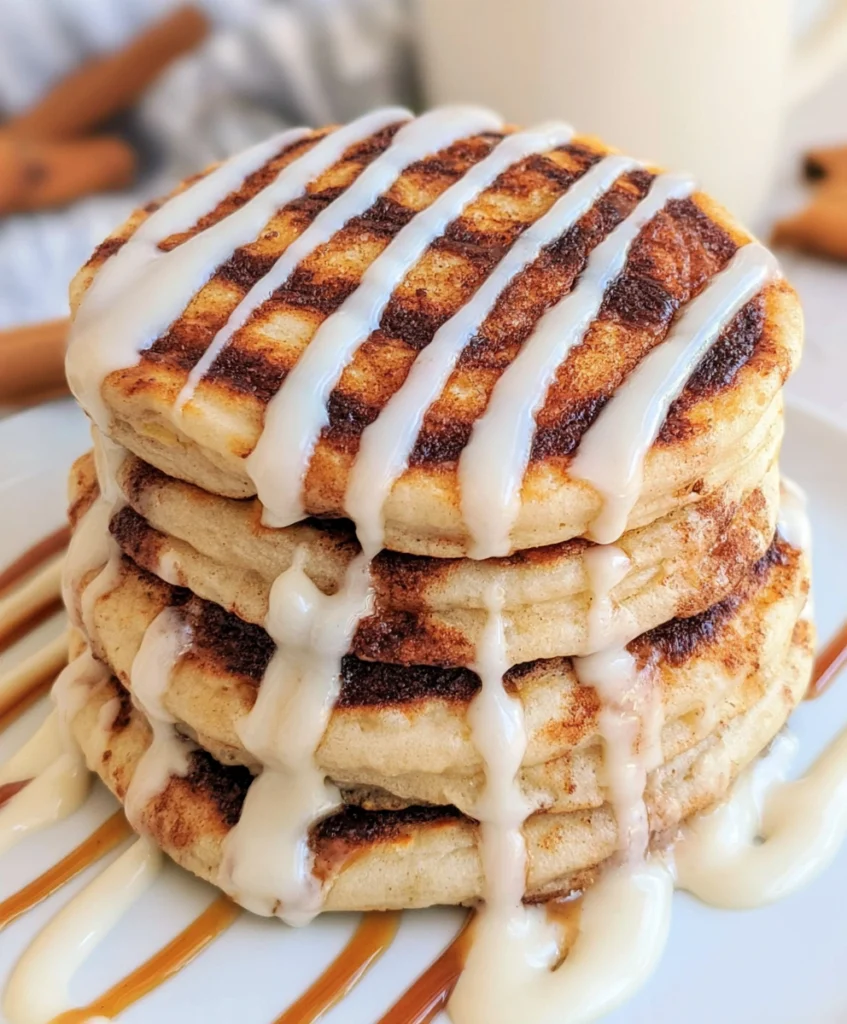 Stack of fluffy cinnamon roll pancakes topped with cream cheese glaze.
