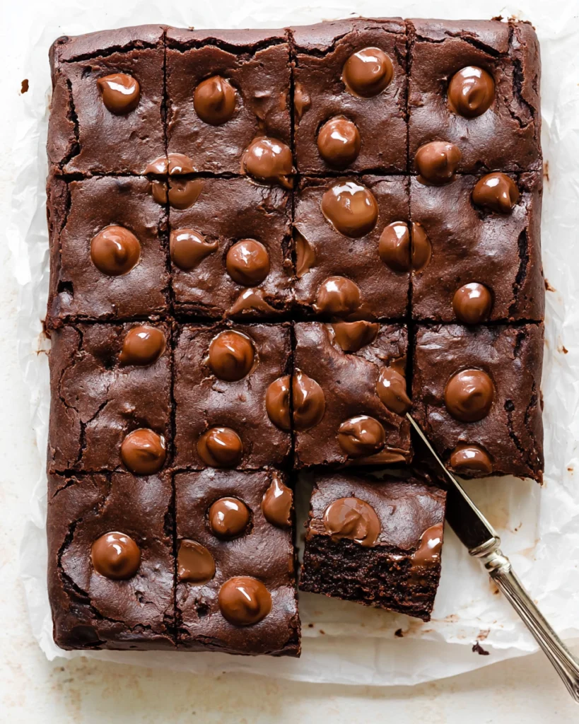 Fudgy Black Bean Brownies 5 Overhead view of fudgy black bean brownies topped with melted chocolate chips, with one square lifted on a knife.